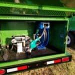 A green truck with a blue and white hose connected to it.