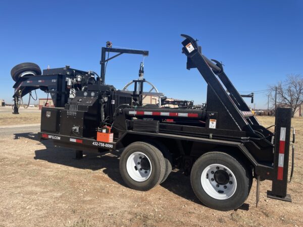 A black tow truck parked on top of a dirt field.