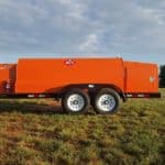 A large orange trailer parked in the grass.