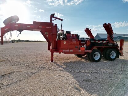 A red log splitter sitting on top of a gravel road.