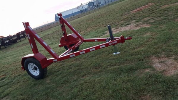 A red trailer is sitting in the grass.