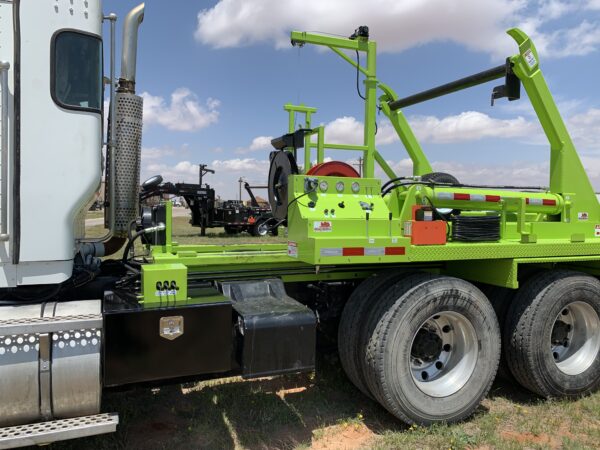 A large green truck parked in the grass.