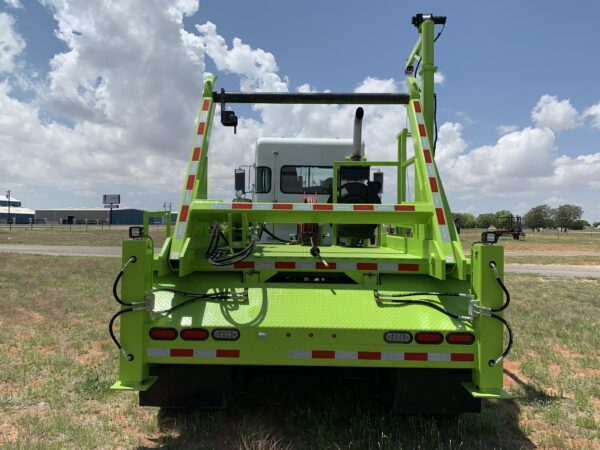 A large green truck parked in the grass.