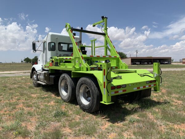 A green tow truck parked in the grass.