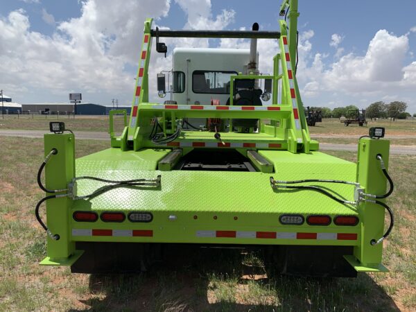 A green truck is parked in the grass.