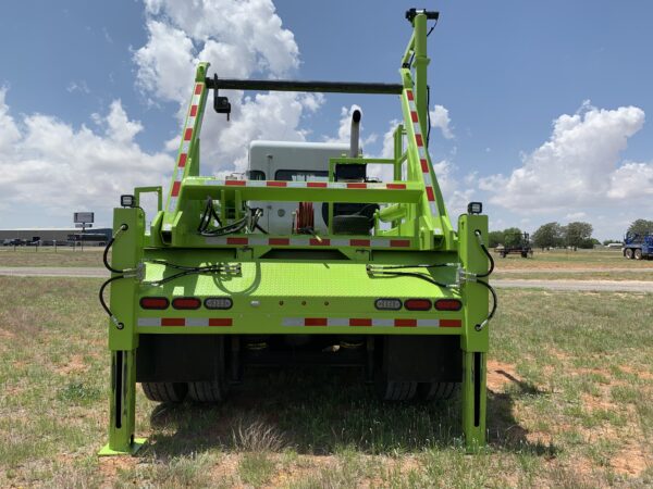 A large green truck parked in the grass.