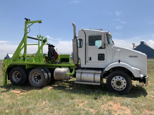 A white truck with green trailer parked in the grass.