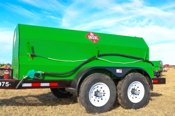 A green dump truck parked in the middle of a field.