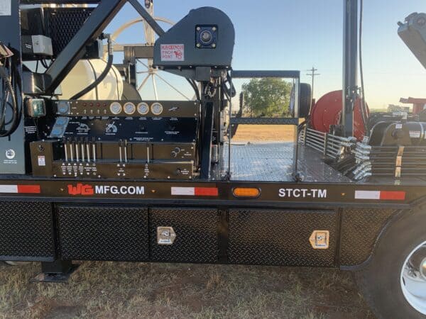 A black flatbed trailer with a large number of equipment on it.