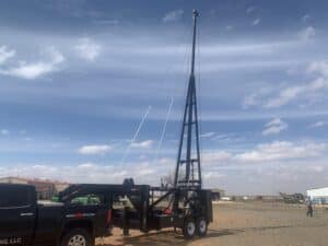 A truck parked in the sand next to a pole.