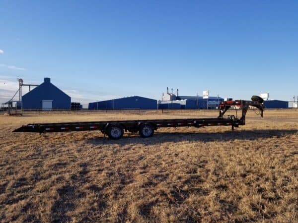 A large trailer is parked in the dirt.