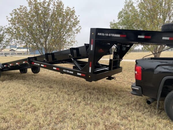 A black trailer with a truck in the background.