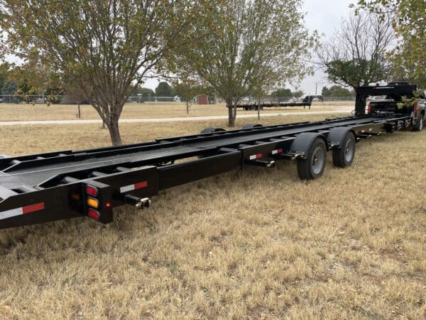 A black trailer is parked in the grass.