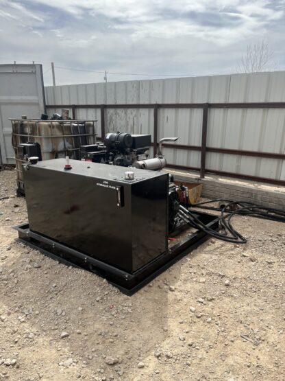 A black box sitting in the dirt near a fence.