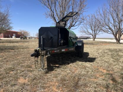 A green and black trailer parked in the grass.