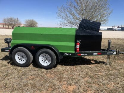 A green trailer with a black grill sitting in the grass.