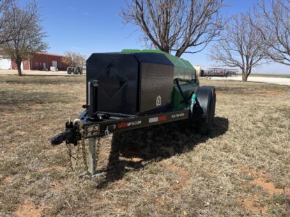 A green trailer with a black tank sitting in the grass.