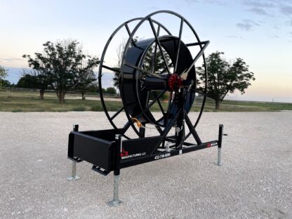 A large black hose reel attached to the side of a road.