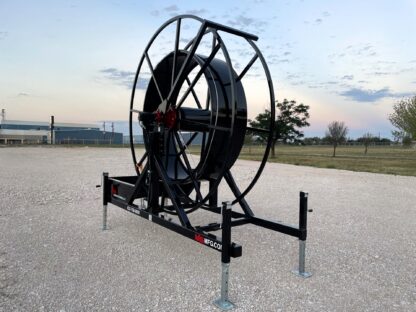 A large black hose reel attached to the side of a road.