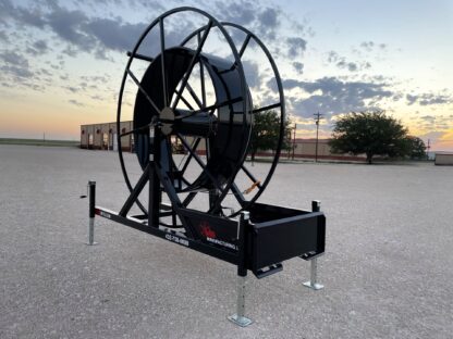 A large black hose reel sitting on top of concrete.