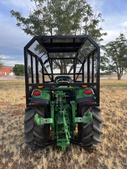 A green tractor with a cage on the back.